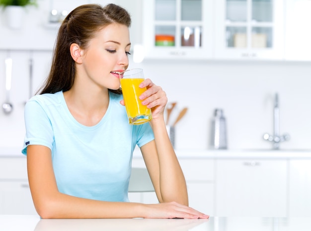 Foto gratuita bella donna beve di succo d'arancia fresco