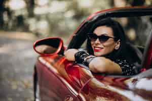 Free photo beautiful woman driving red cabrio