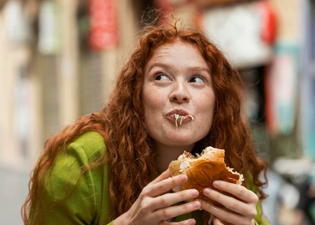 Foto gratuita bella donna che mangia delizioso cibo di strada all'aperto