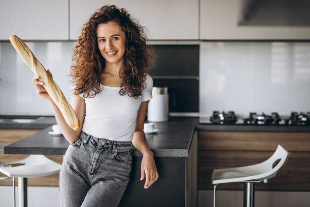 Beautiful woman eating fresh bread at the kitchen