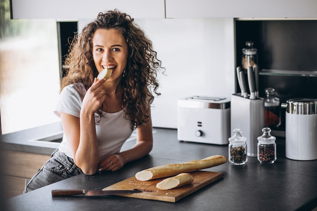 Bella donna che mangia pane fresco alla cucina