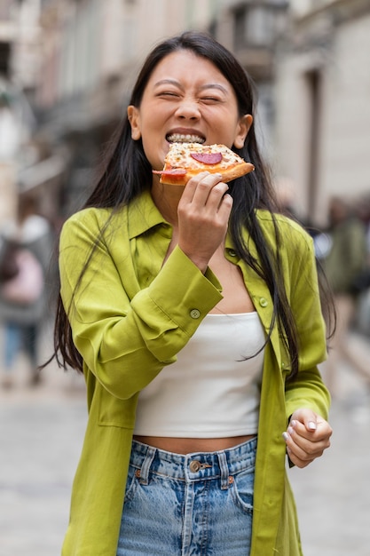 Free photo beautiful woman eating street food outdoors