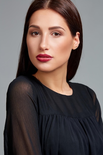 Beautiful woman face close up portrait young studio on gray. Woman in black dress