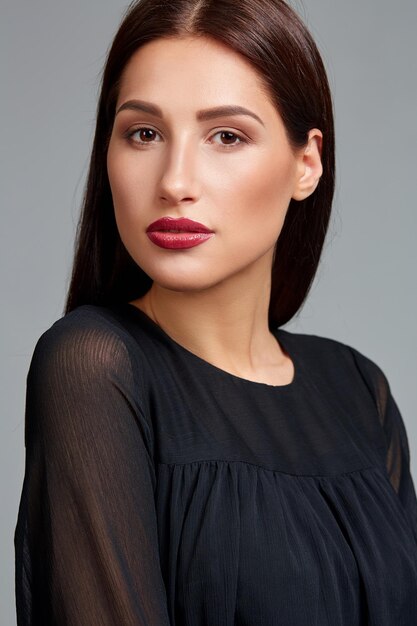 Beautiful woman face close up portrait young studio on gray. Woman in black dress