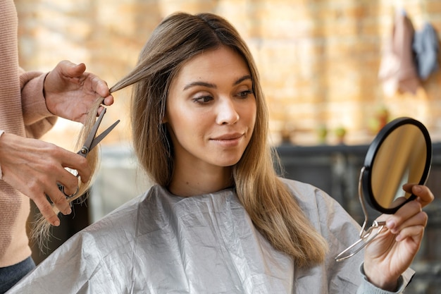 Free photo beautiful woman getting her hair cut at home by hairstylist