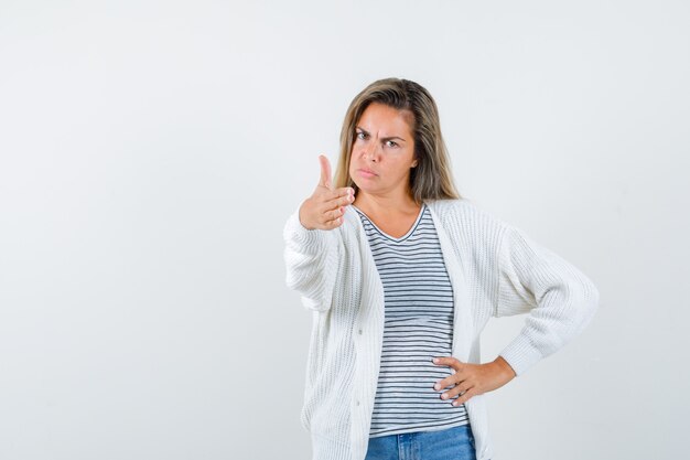 Beautiful woman giving hand for shaking in jacket and looking serious. front view.