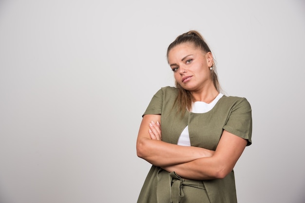 Beautiful woman in green shirt posing on gray wall.