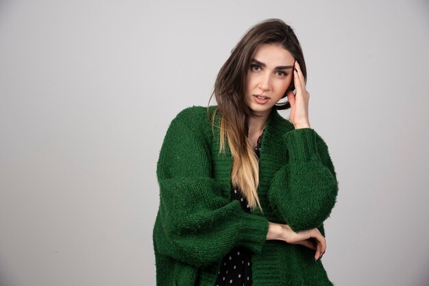 何かを考えている緑のセーターの美しい女性。