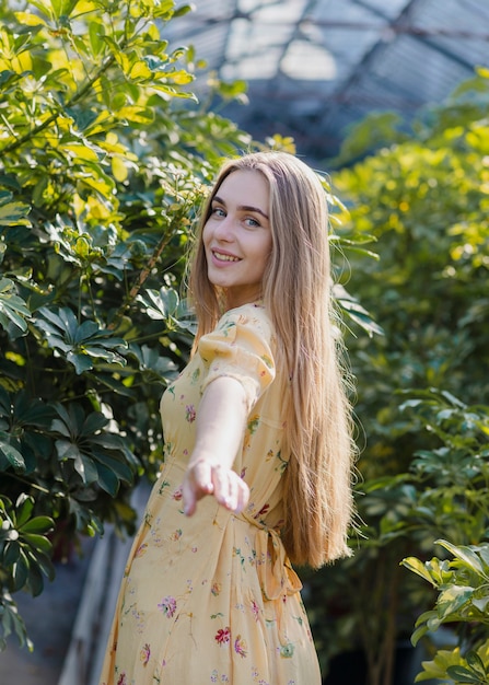 Free photo beautiful woman in greenhouse with hand  stretched