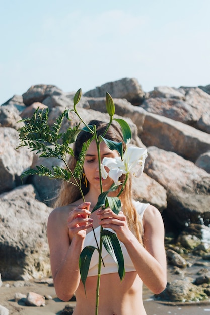 Free photo beautiful woman holding branches in front of her face at beach