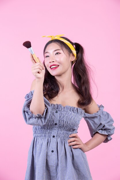 Free Photo beautiful woman holding a brush, brushed on a pink background.