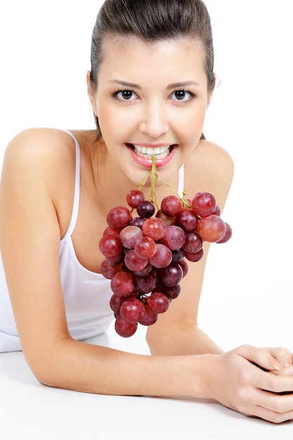 Foto gratuita bella donna che tiene un grappolo d'uva dai suoi denti