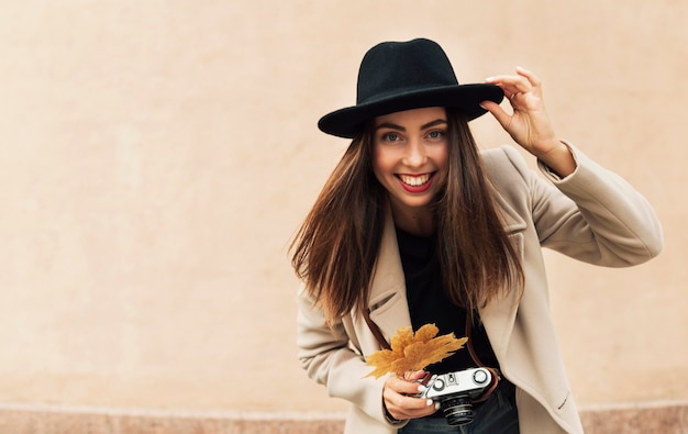 Foto gratuita bella donna che tiene una macchina fotografica e una foglia