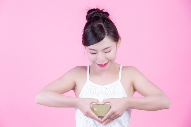 Beautiful woman holding a card on a pink background.