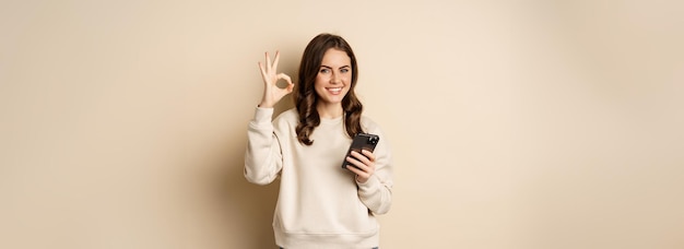Бесплатное фото Красивая женщина с мобильным телефоном, мобильным телефоном и хорошим знаком, рекомендующим приложения для покупок