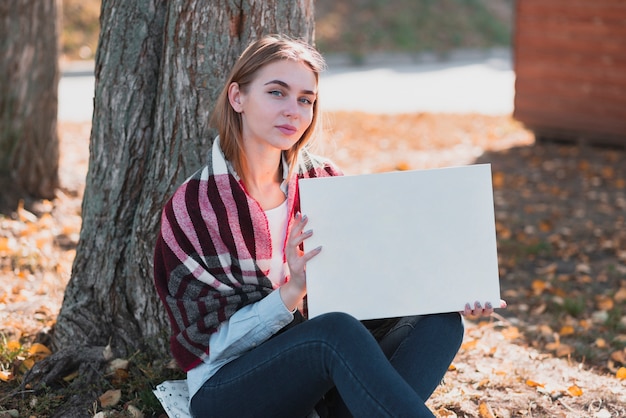 Free photo beautiful woman holding a frame with mockup