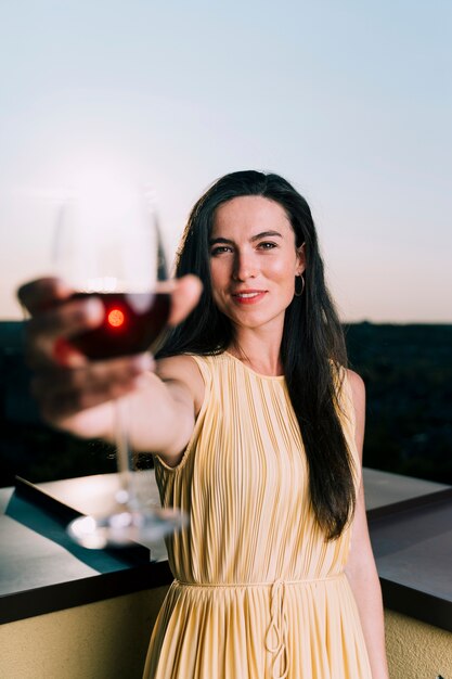 ワインのグラスを保持している美しい女性ぼやけて前景