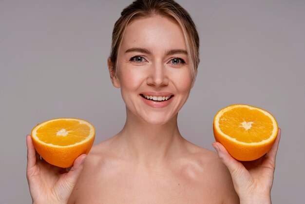 Beautiful woman holding halved orange