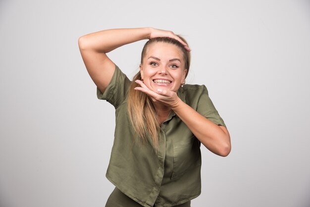 Beautiful woman holding her chin on gray wall.