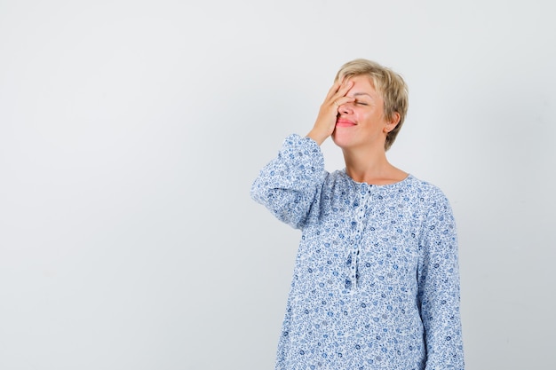 Beautiful woman holding her hand on face in patterned blouse and looking tired , front view. space for text