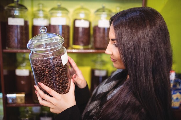 Beautiful woman holding jar of coffee beans