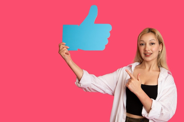 Beautiful woman holding a like button isolated on pink background
