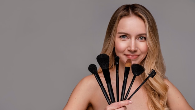 Foto gratuita bella donna che tiene i pennelli per il trucco