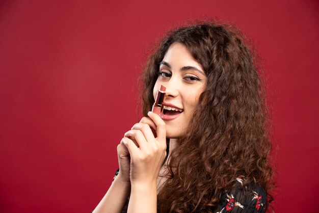 Beautiful woman holding nude lipstick.