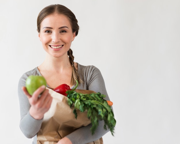 Beautiful woman holding paper bag with fruits and vegetables