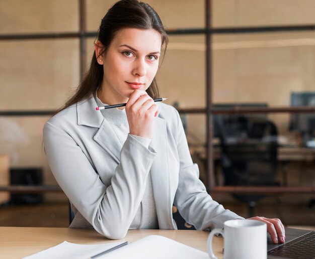 Beautiful woman holding pencil looking at camera