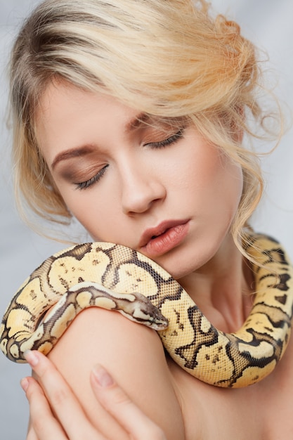 Free photo beautiful woman holding a python, which wraps around her body