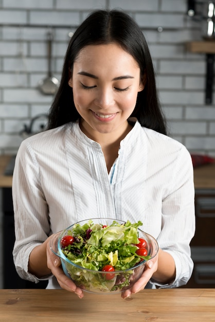 Beautiful woman holding salad in bowl