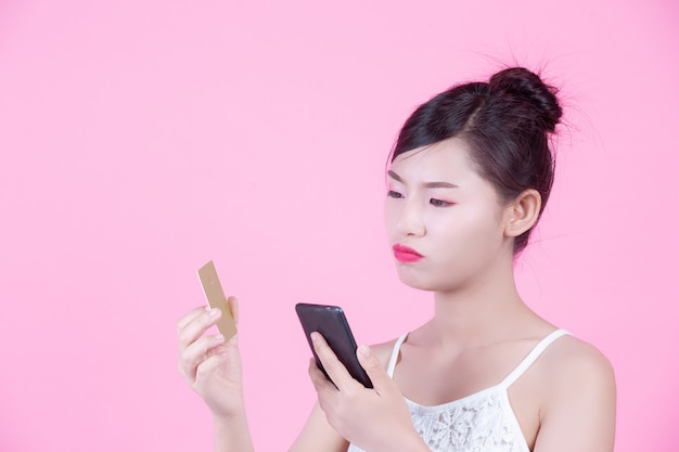 Красивая женщина, держащая смартфон и карты на розовом фоне