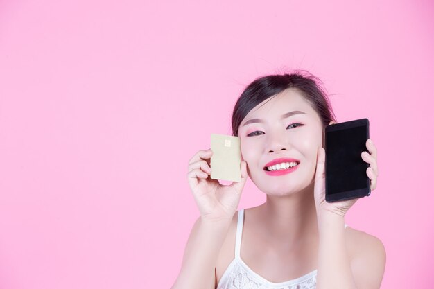 Красивая женщина, держащая смартфон и карты на розовом фоне