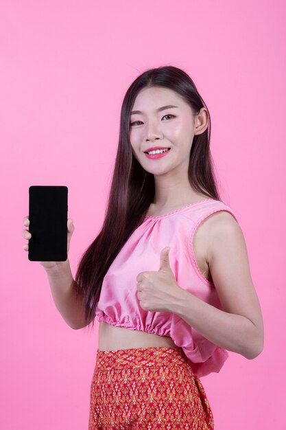 ピンクの背景にスマートフォンを持って美しい女性。