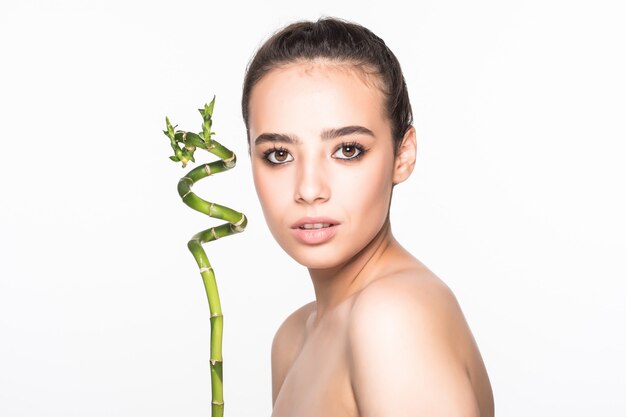 Beautiful woman holding a stick of bamboo on a white wall