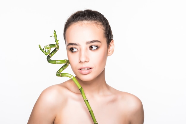 Beautiful woman holding a stick of bamboo on a white wall