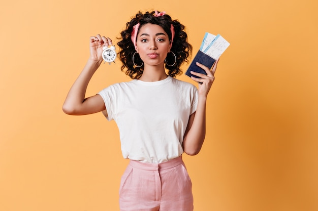 Beautiful woman holding tickets and alarm clock