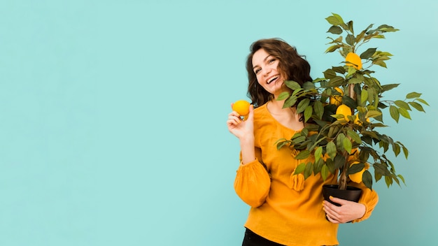 Free photo beautiful woman holding a tree with copy space