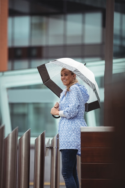 Foto gratuita bella donna con ombrello e in piedi sulla strada