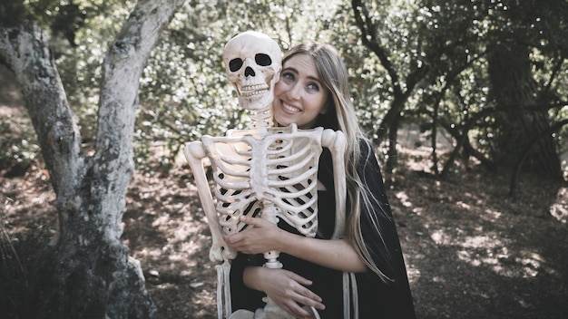Beautiful woman hugging behind skeleton