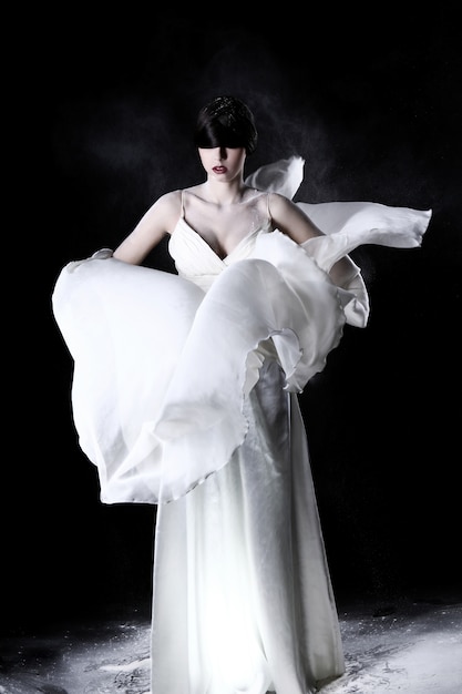 Бесплатное фото Красивая женщина в белом платье и летающей пыли