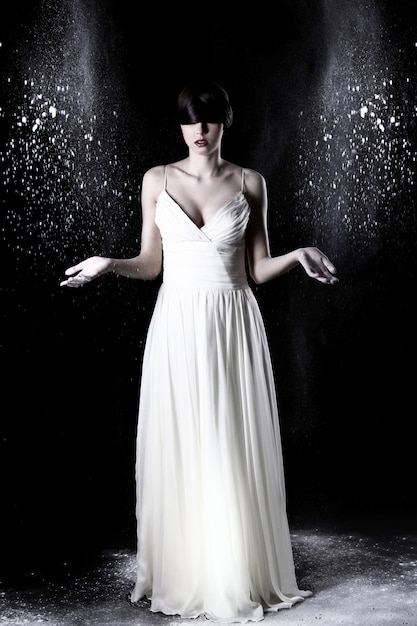 무료 사진 하얀 드레스와 비행 먼지에서 아름 다운 여자