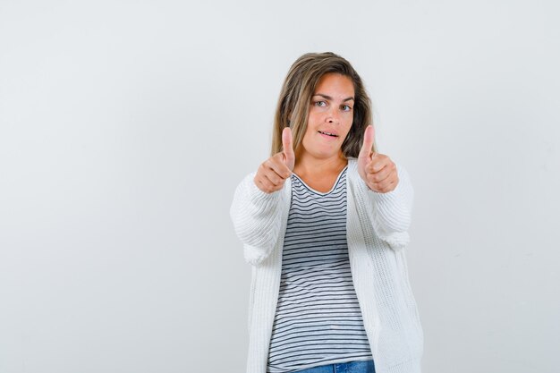 Beautiful woman in jacket showing thumbs up and looking satisfied , front view.