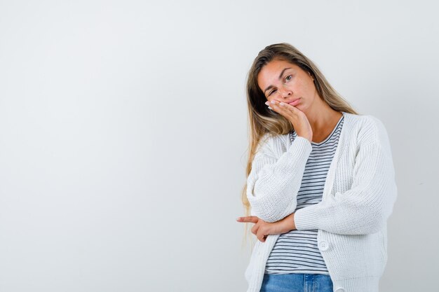 Beautiful woman leaning cheek on palm in jacket and looking tired , front view.