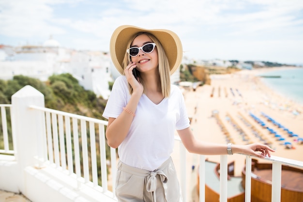 Beautiful woman leaning on the terrace railing, relaxing and having a phone call