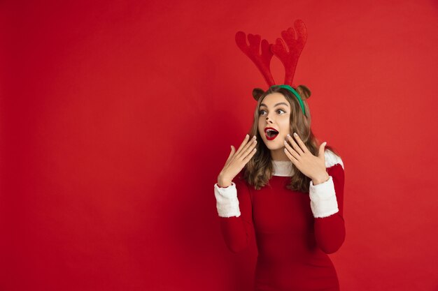 빨간 벽 개념에 고립 된 크리스마스 사슴 같은 아름 다운 여자