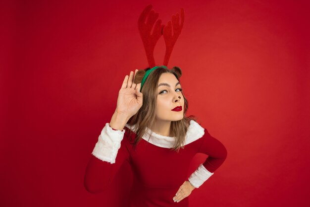 Beautiful woman like christmas deer isolated on red wall concept 