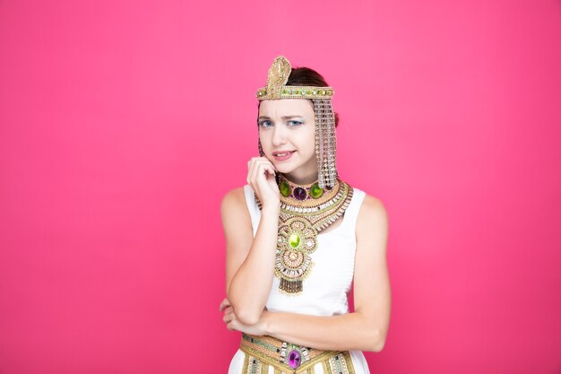고대 이집트 의상을 입은 클레오파트라 같은 아름다운 여성은 분홍색에 혼란스럽고 걱정스럽다