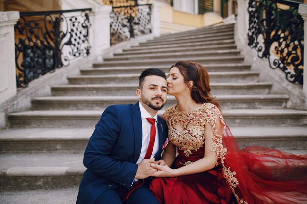 Beautiful woman in a long red dress walks around the city with her husband 